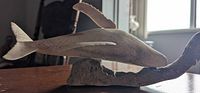 Left side profile showing whale figure on driftwood base