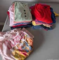 Stack of folded tops including mint vest and Beatles graphic tee