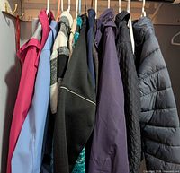 Row of nine assorted women’s jackets and sweaters on hangers