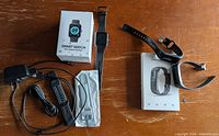 Group shot of smart watch, fitness tracker, boxes, cables and straps on table