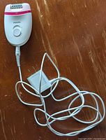 Front view of Philips epilator with attached power cord and adapter