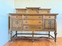 front view of carved oak sideboard showing drawers, cabinets, legs, stretcher
