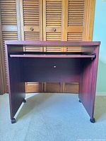 Front view of cherry laminate computer desk showing keyboard tray and casters