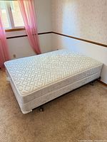 Full mattress on box spring atop metal frame in room