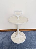 Front view of white molded resin pedestal side table on carpet