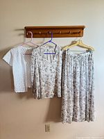 Blouse, skirt, and cardigan hanging on peg rack