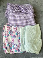 All five bedding pieces stacked: gingham bed skirt on top, butterfly and blue sheets below
