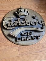 Front view of round Carlsberg On Draft sign showing full design