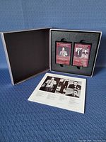 Open presentation case showing two maroon-label cassettes and insert sheet
