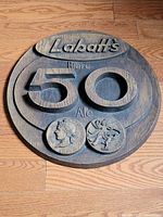 Full view of round Labatt's 50 Ale faux wood sign on floor