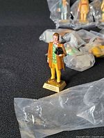 Single figurine on base plus others in bags