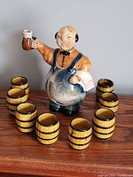 Front view of bartender decanter surrounded by eight barrel cups