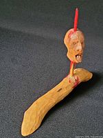 Overall view of carved wood head on stake and base