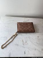 Front view showing brown monogram exterior and gold-tone chain keyring