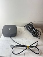 Docking station with attached USB-C cable and separate power adapter on marble surface