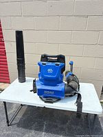 Front view of blower body, hose and nozzle on table