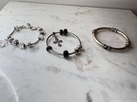 Three silver-tone bracelets laid out on surface