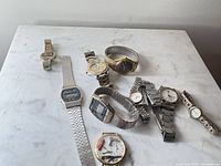 Group of eight mixed-metal wristwatches on surface