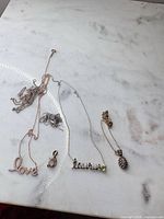 Overview of five sterling silver necklaces and pendants laid on marble surface