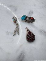 Overview of earrings, brooch, and pendant on marble surface