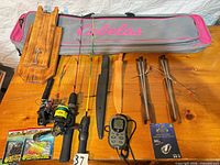 Overall lot layout on table showing case, rods, reels, knife, scale, lures, stands, wooden holder
