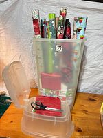 Tall translucent tub holding multiple wrapping paper rolls