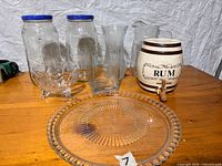 Overall view of ceramic rum dispenser, glass jars, vases, platter, pitcher and bottle
