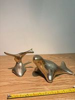 Seal and whale tail sculptures side by side with tape measure for scale