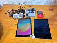 Full lot showing two iPads, grey console, red handheld, controllers and cables