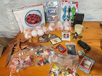Overview of entire lot on table showing boxed snow tube, sealed blisters, bags of LEGO, sandals, cards, radio and other items