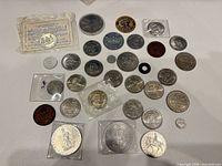 All items laid out showing variety of coins, tokens, medallions, wooden nickel