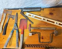 Group shot showing most tools: axes, shears, shovel, grease gun, level, hand brace, auger bits