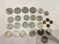 All 26 coins laid out: Eisenhower dollars top rows, Kennedy halves middle, Susan B. Anthony dollar and four Lincoln pennies at lower right