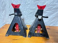 Pair of black and red steel jack stands on wooden surface
