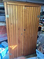 Front view of closed wardrobe showing vertical slat doors and honey finish