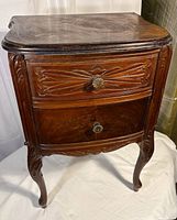 Front view of carved two-drawer end table showing drawer fronts, brass pulls and cabriole legs