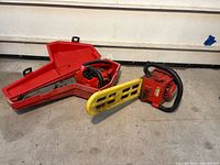 Homelite chainsaw with yellow bar cover and red scabbard/case