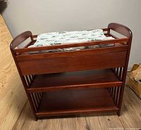 Front view of wooden baby changing table with shelves and change pad