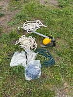 Anchor, float and assorted rope coils on grass