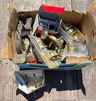 Overview of box containing assorted door knobs and handle