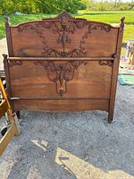 Front view of carved wood headboard and footboard leaning upright