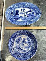 Top view of oval platter and round plate showing blue willow scenes