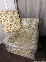Armchair wrapped in plastic with detached seat cushion