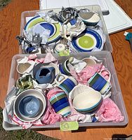 Two totes holding striped stoneware plates, bowls, mugs and pitcher