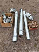 Lot overview showing three round ducts, box of fittings, box of floor registers