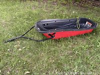 Top view of red Pelican sled with black tow bar on grass