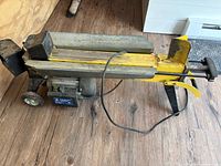 Side view of Power Fist electric wood splitter showing motor housing, wheels, splitting beam, and power cord