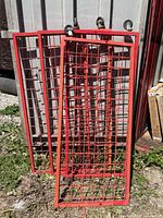 Three red steel grid panels leaning against structure