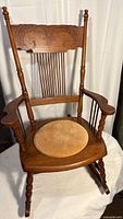 Full view of carved wood rocking chair with leather cushion