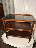 Full front view of wooden 3-tier bar cart on casters